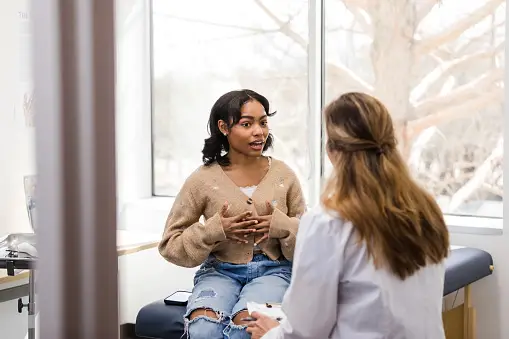 A woman receiving gynecological care in an office, she is talking to a gynecologist doctor.